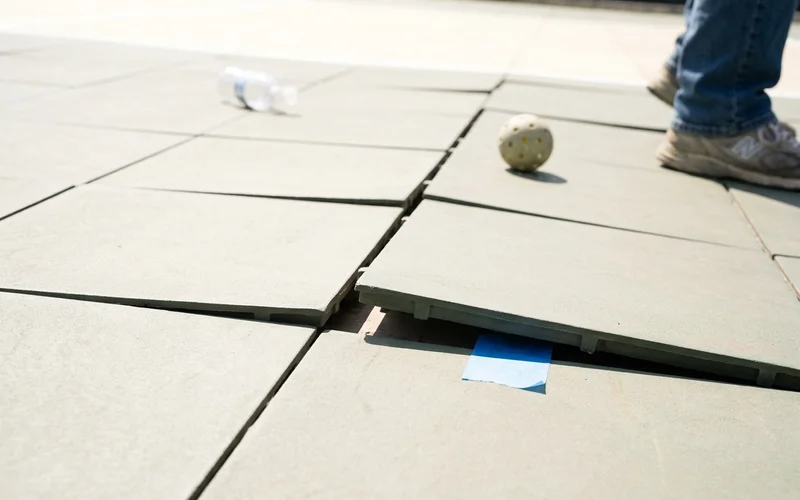 Interlocking modular tile joints showing gaps and edge lift after heat exposure