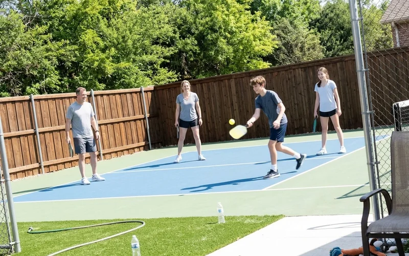 Family playing on a finished backyard court on a bright spring morning