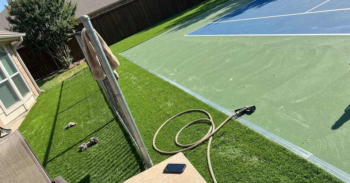 Sport court surrounded by clean artificial turf with straight edging between surfaces