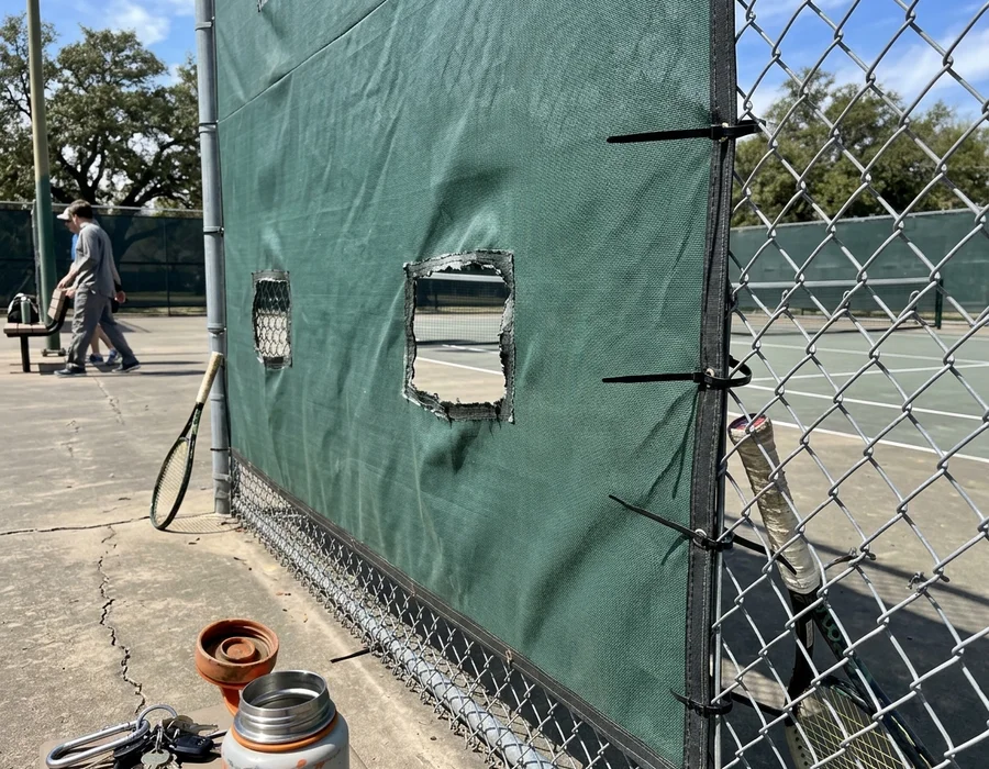 HDPE windscreen with blowout vents fitted to a court fence